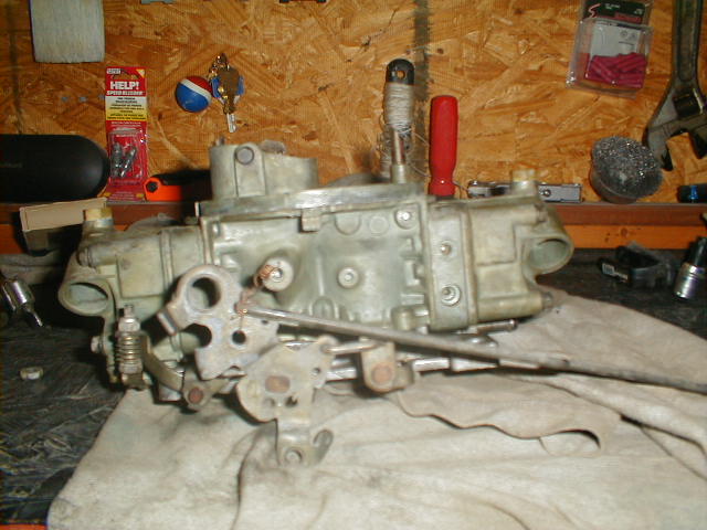 Carburetor on a workbench with tools and supplies in the background