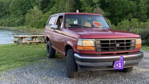 1994 Ford Bronco - This 1994 Ford Bronco is parked outdoors near a body of water, with a 'For Sale' sign visible on its dashboard.