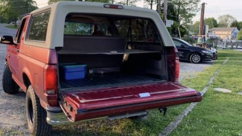 1994 Ford Bronco - The rear of a red SUV is shown with its tailgate down, revealing the cargo area.