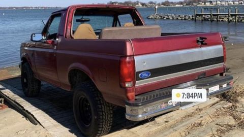 1994 Ford Bronco - This red Ford Bronco, likely from the early 1990s, is parked on a wooden ramp by the water.