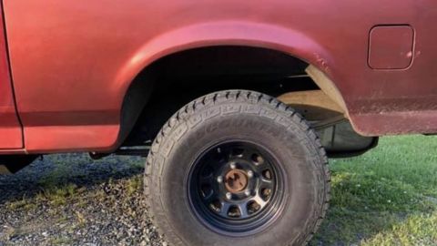 1994 Ford Bronco - Close-up of the rear wheel well and tire on a red SUV, consistent with a 1992 Ford Bronco.