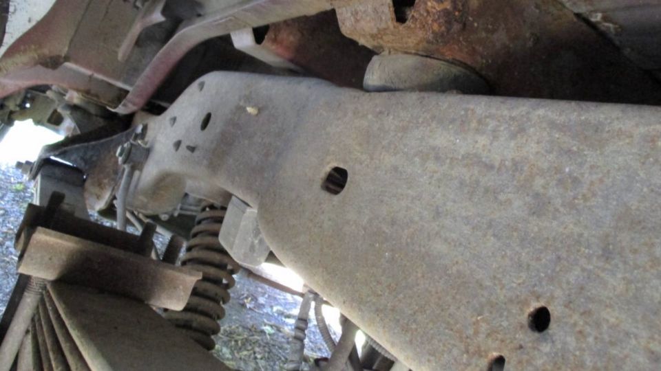 Underside view of rusty vehicle frame and suspension components