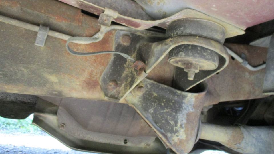 Close-up of rusty vehicle frame with suspension mount and rubber bushing