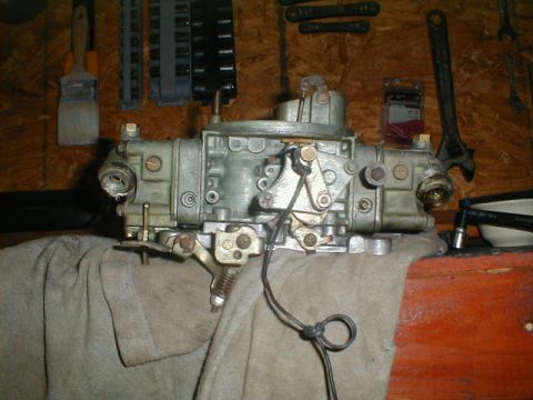 1967 Ford Mustang - A carburetor sits on a cloth-covered surface, with various tools hanging on the wall behind it.