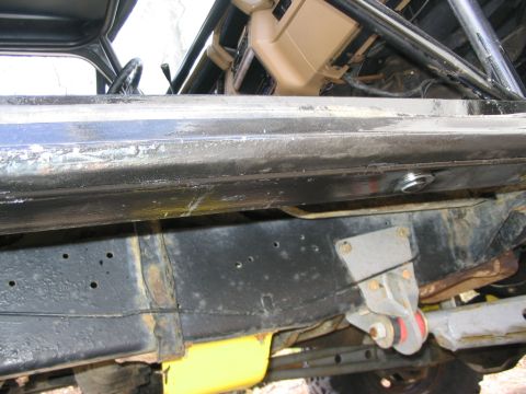 1986 Ford Bronco - Close-up view of the undercarriage and frame of a vehicle, showing suspension components and a fuel tank.