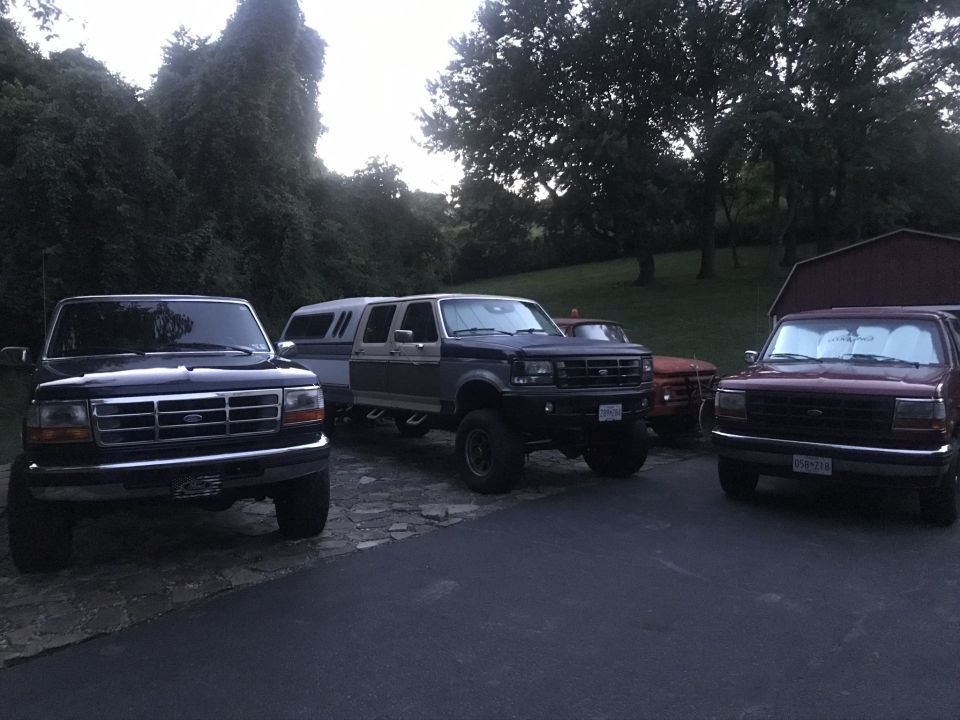 Four pickup trucks parked on a stone driveway.