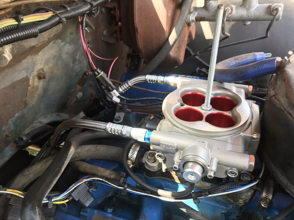 Engine bay with silver throttle body, red intake ports, hoses, and wires.