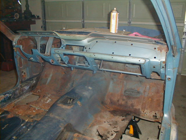 1967 Ford Mustang interior, showing rusted floor pans and a disassembled dashboard with a spray can on top