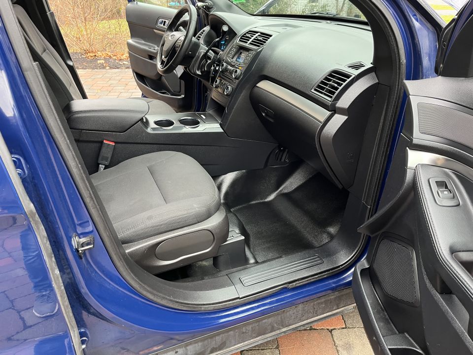 Front cabin and footwell of a blue Ford Explorer through open door