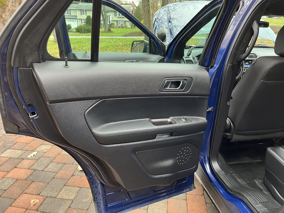 Rear door panel of a blue SUV shown with door open over a brick driveway