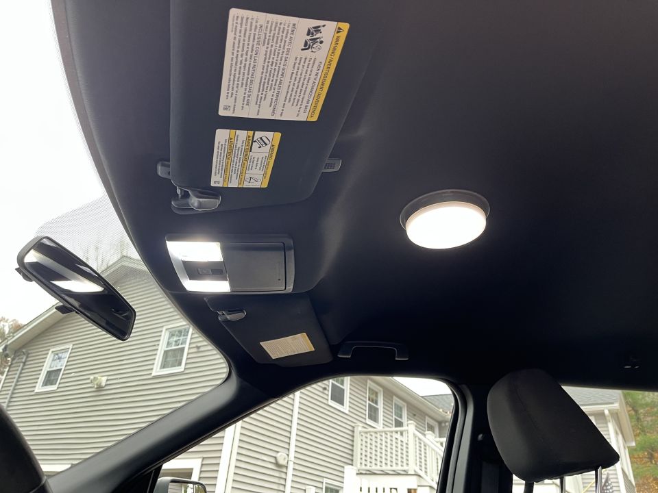 Vehicle headliner with overhead console, dome light, and visor warning labels
