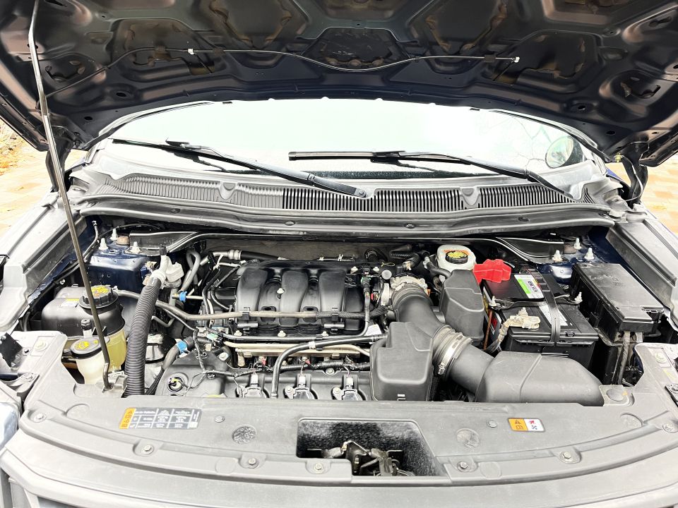 Engine compartment showing V6 engine, battery, and reservoirs