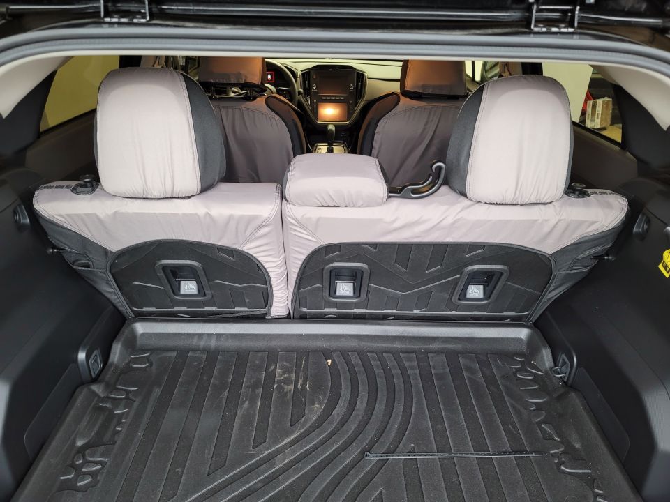 Rear interior of a Subaru Impreza with protective seat covers and a cargo mat.