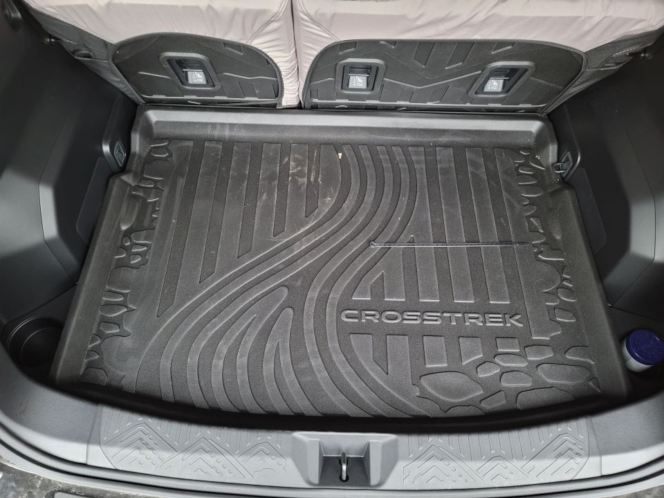 Black rubber cargo mat with "CROSSTREK" text inside a vehicle's trunk.
