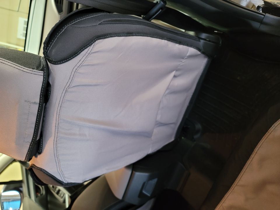 Close-up of a light gray seat cover with dark gray trim in a vehicle interior.