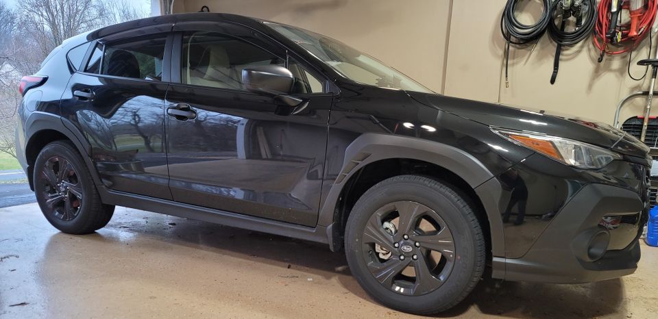 Black Subaru Crosstrek parked in a garage, front passenger side view.