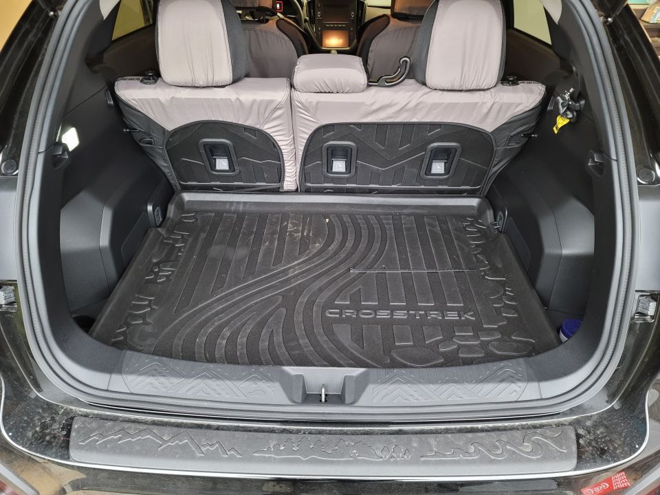 Black Subaru Crosstrek cargo area with all-weather mat and folded rear seats.
