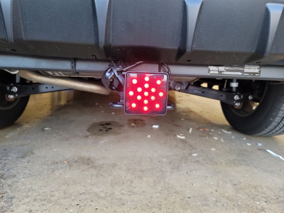 Rear view of a vehicle with a square red LED light mounted below the bumper.