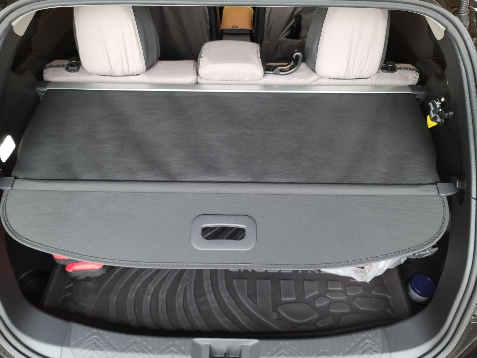 Interior cargo area of a vehicle with rear seats and a closed cargo cover.