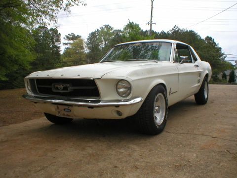 1967 Ford Mustang - A white 1967 Ford Mustang coupe is parked outdoors on a concrete surface.