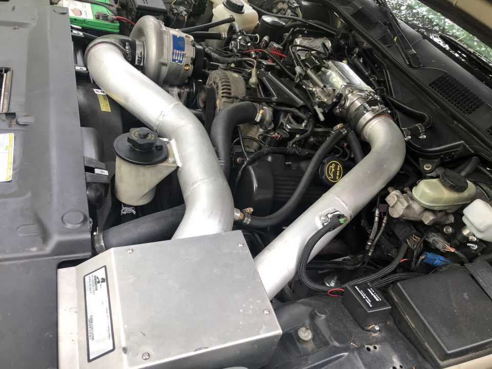 Mercury Grand Marquis engine bay with supercharger and polished aluminum intake piping.