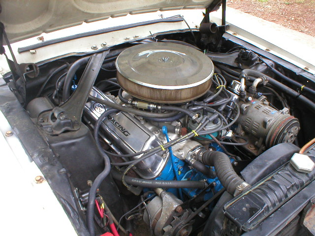 engine bay with chrome valve covers that say "RACING", air cleaner, and AC compressor