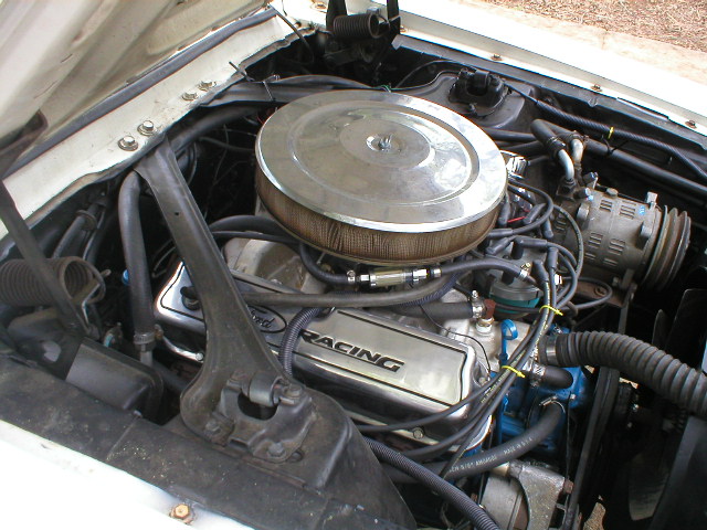 Ford V8 engine bay showing chrome air cleaner, "RACING" valve covers, and air conditioning compressor