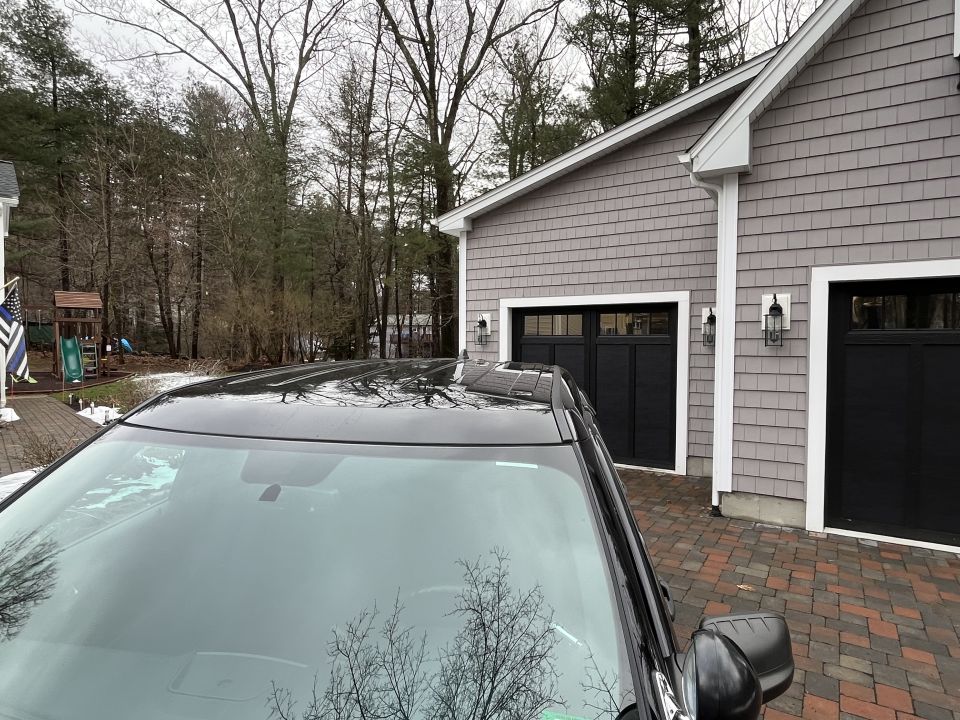Black SUV windshield and roofline looking toward a garage