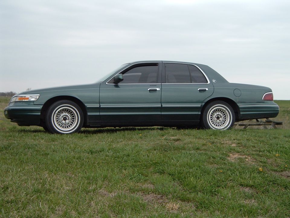 Green 1995 Mercury Grand Marquis sedan parked on grass, side view
