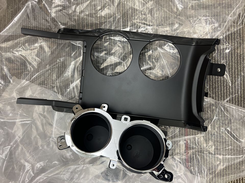 Black dash instrument bezel and chrome-ringed dual gauge housing on plastic sheeting
