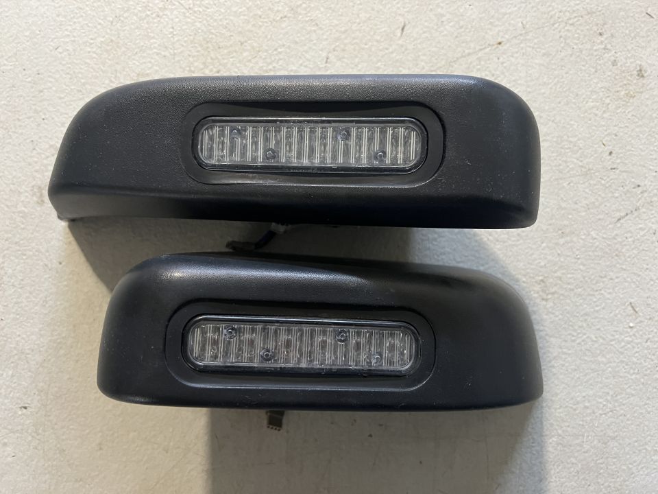 Two black automotive side mirror caps with integrated LED lights