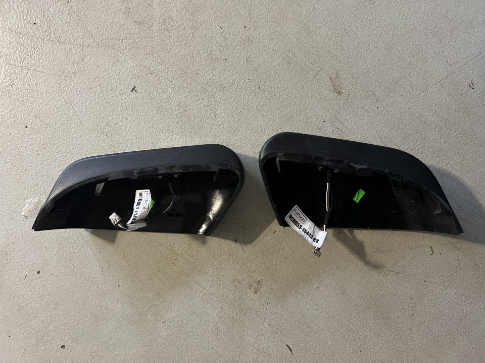 Two black Ford Explorer mirror caps, interior view, with labels.