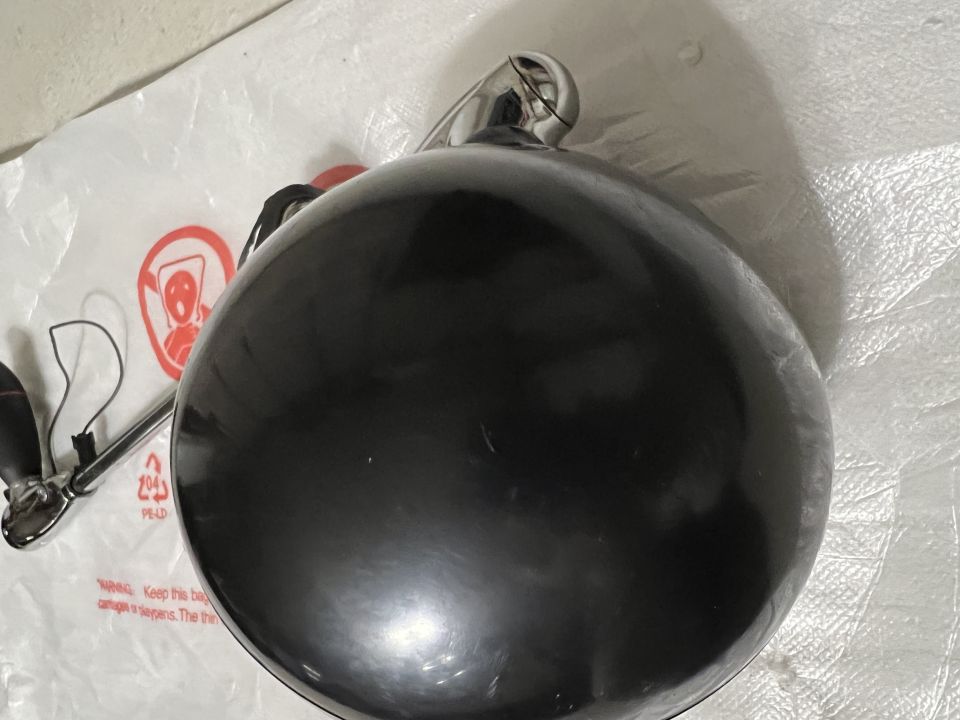 Black spherical object with metal loop on white plastic bag