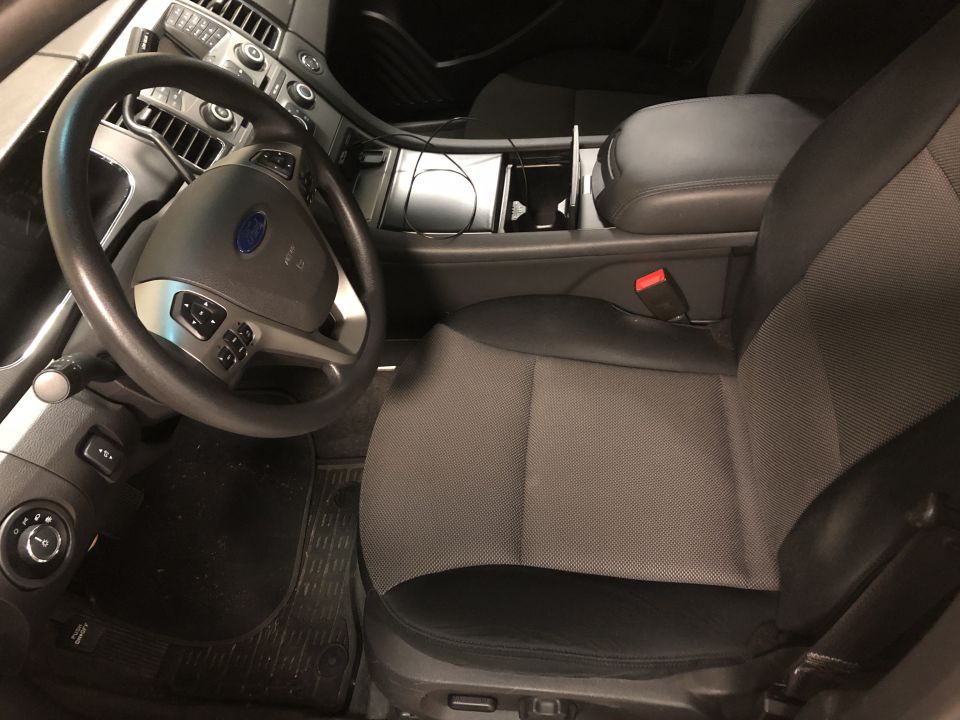 Interior of a Ford Taurus showing driver's seat, steering wheel, and center console.