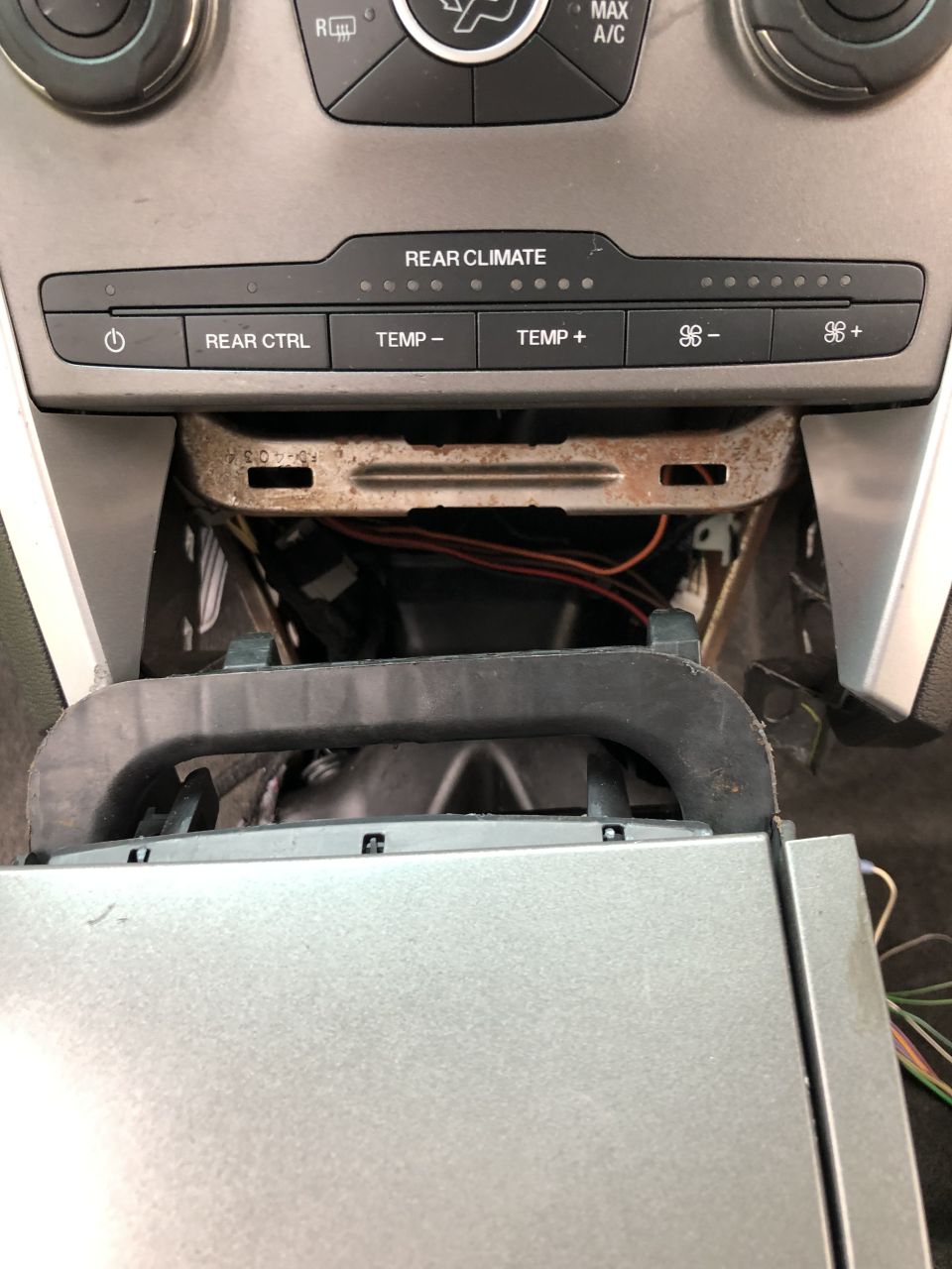 Vehicle center console climate controls with disassembled lower section showing wires.
