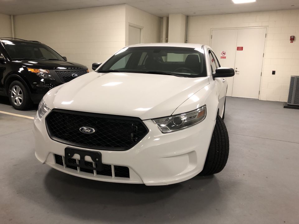 White Ford Taurus sedan parked in a garage.