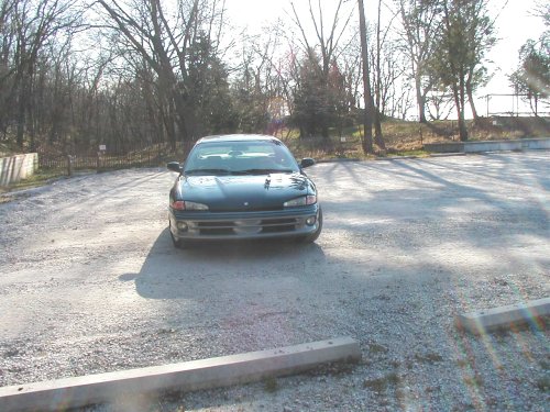 Front view of dark teal Dodge Intrepid sedan parked on a gravel lot in woods