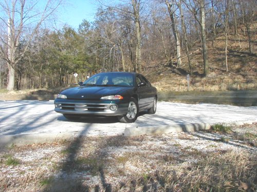 Dark green 1995 Dodge Intrepid parked on a gravel lot with trees in the background