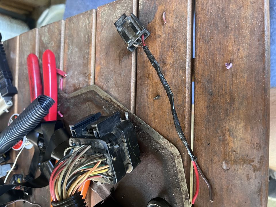 Taped wiring pigtail connector and cut multi-pin harness connector on a wooden work table