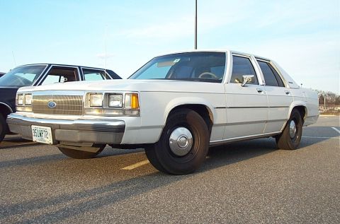 1991 Ford LTD Crown Victoria - A white 1991 Ford Crown Victoria LTD is parked in a lot, with another vehicle visible behind it.