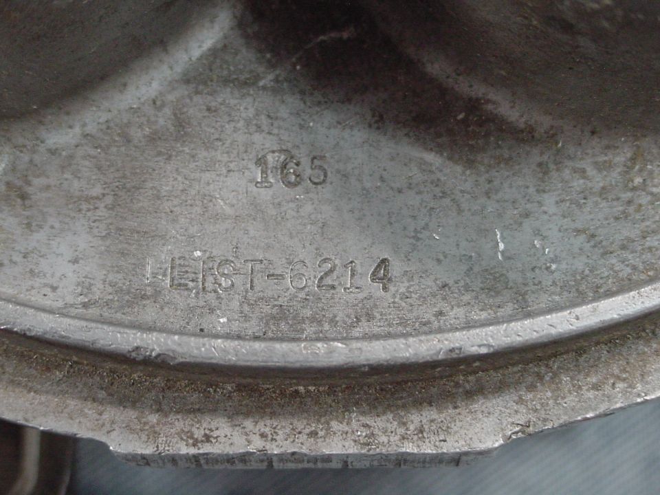 Close-up of a metal vehicle part with embossed text "165" and "LIST-6214"
