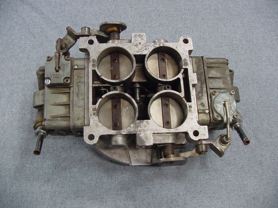 Four-barrel carburetor with visible throttle plates, top-down view.