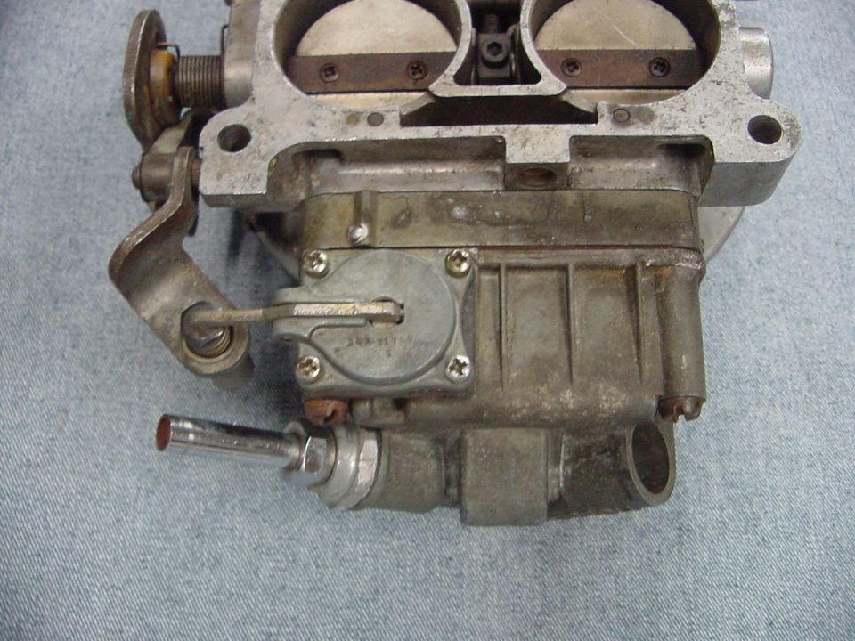 Close-up of a vintage carburetor with linkages and fuel fitting