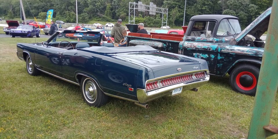 1969 Mercury Cougar convertible parked next to a weathered pickup truck with hood open