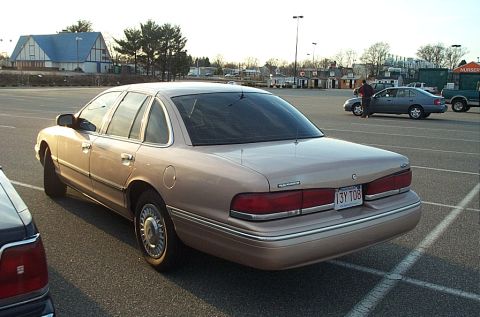 1991 Ford LTD Crown Victoria - A tan 1991 Ford Crown Victoria LTD is parked in a lot, showing its rear end and license plate.