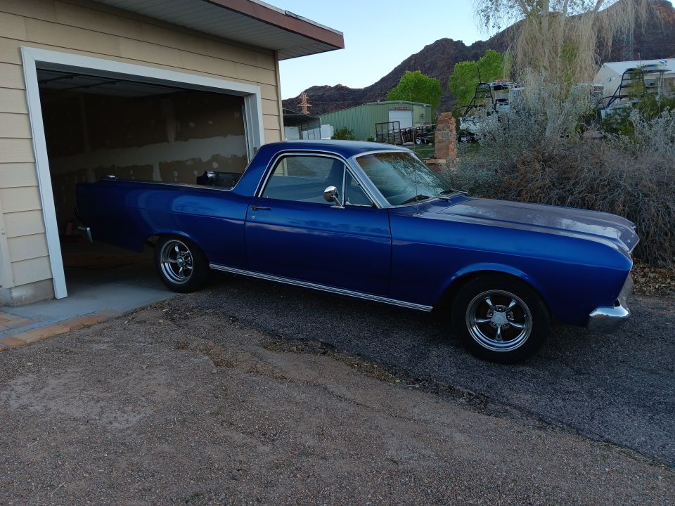 Blue 1966 Ford Falcon Ranchero parked in front of a garage