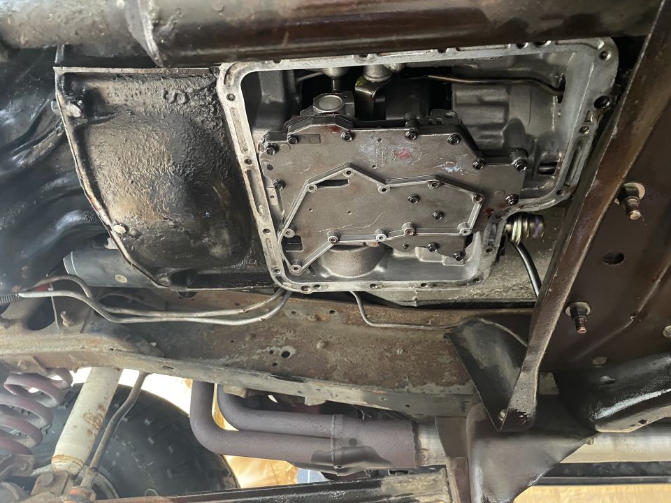 Underside of a vehicle showing the transmission pan, valve body, suspension, and exhaust.