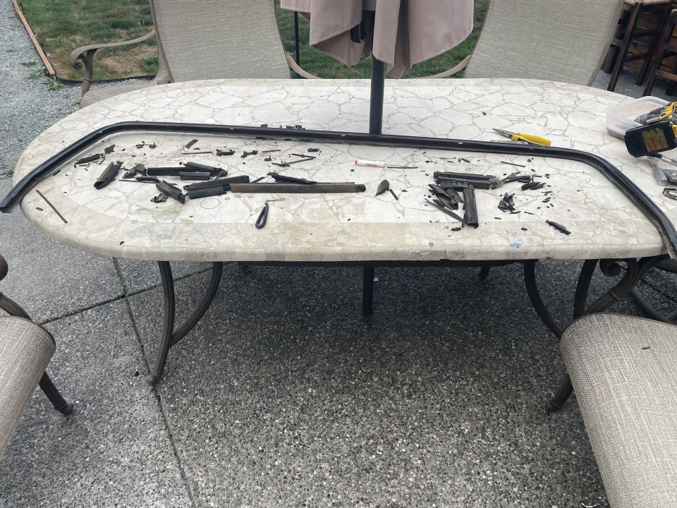 Disassembled black rubber trim piece and tools on an outdoor table.