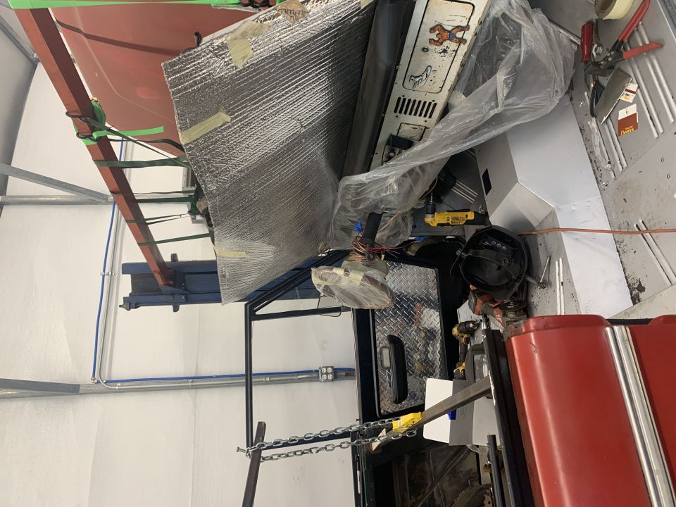 Interior of a vehicle under construction, showing insulation, tools, and parts.