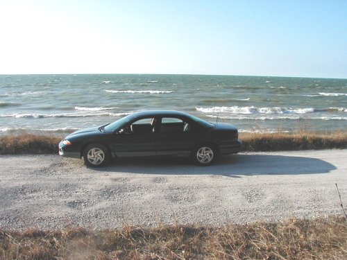 Side view of a black 1995 Dodge Intrepid parked by the ocean